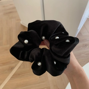 Close-up of black velvet scrunchie decorated with large white pearls for hair styling