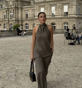 Detail of elegant brown halter top and wide-leg trousers set with a black handbag