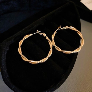 Detail of twisted rope gold hoop earrings presented in a black velvet jewelry box