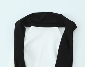 Dettaglio di cuciture a contrasto in raso nero e maglia bianca su abito halter