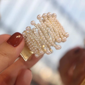 Close-up of elegant gold hair claw clip with ivory pearls and ribbed metal base details