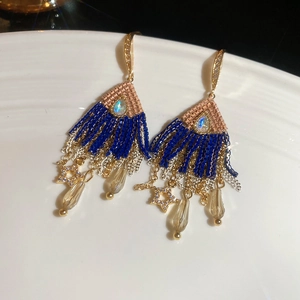 Detailed macro of crystal tassel earrings with star and teardrop charms on ceramic