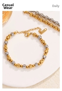 Detailed macro view of two-tone beaded bracelet with textured metal beads and lobster clasp
