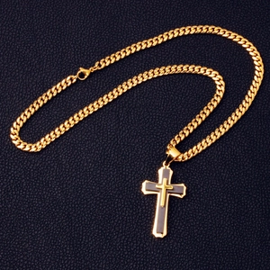 Macro detail of a double-layer gold and black cross pendant on a classic Cuban chain