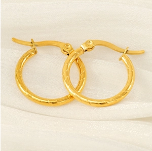 Macro shot of gold-plated hoop earrings with elegant spiral texture and hinge clasp