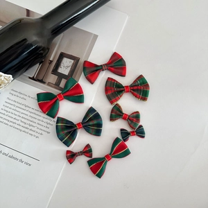 Detailed flat lay of red and green plaid Christmas bows with gold edges and festive props