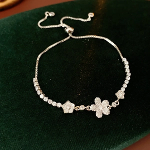 Dettaglio macro del bracciale a fiori d'argento con zirconi su velluto verde