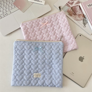Flat lay of quilted heart laptop sleeves in pink and blue with bow and zipper details