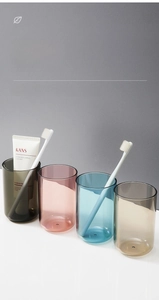 Detail view of four translucent bathroom cups in gray, pink, blue, and gold colors