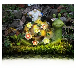 Detail of solar garden snail statue with glowing flowers and Welcome gnome sign