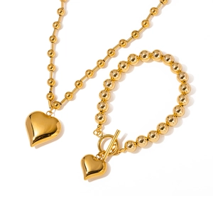 Golden stainless steel jewelry set featuring heart pendant necklace and bead bracelet with OT buckle