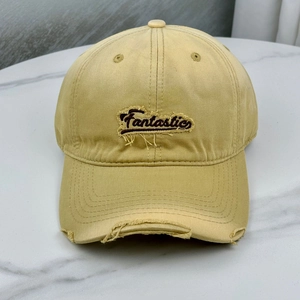 Detail of embroidered Fantastic lettering and distressed brim on light yellow baseball cap