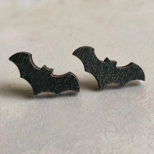 Close-up of black wooden bat stud earrings for Halloween, featuring natural wood texture