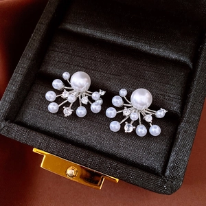 Detail of silver pearl stud earrings with zircon sunburst pattern in a jewelry box