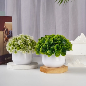 Detail of two artificial potted plants with white round pots on a minimalist desk setup