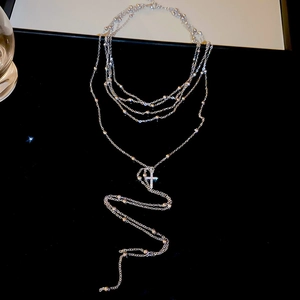 Detail view of silver multi-layer chain necklace with zircon cross pendant on black background