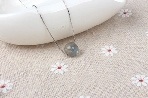 Detail of S925 silver necklace featuring a natural moonstone pendant on ceramic surface