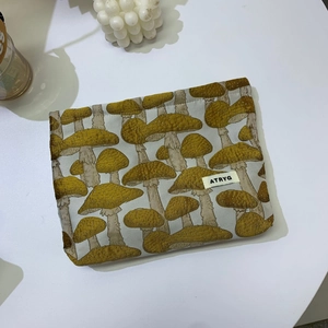 Detail of beige mushroom jacquard travel makeup bag with ATRYG label on white desk