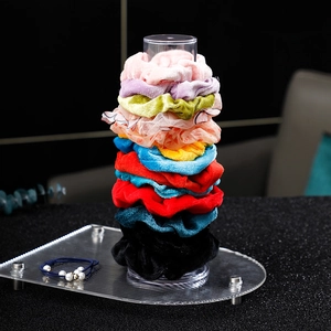 Gros plan d'élastiques à cheveux en velours colorés sur un support vertical en acrylique