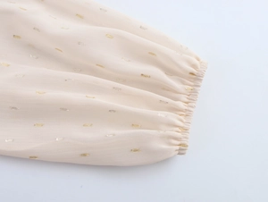 Close-up of beige chiffon sleeve with gold metallic details and elastic pleated cuffs