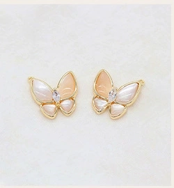 Macro shot of gold butterfly pendant earrings with shell wings and zircon center