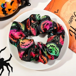 Close-up of black Halloween scrunchie with colorful pumpkin patterns on a white plate