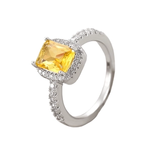 Macro shot of silver ring with large rectangular yellow gemstone and zircon pavé detail