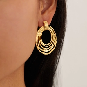 Macro shot of layered gold titanium steel hoop earrings with textured finish on ear