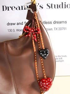 Detail of creative polka dot heart and bow pendants on leather straps with rivets