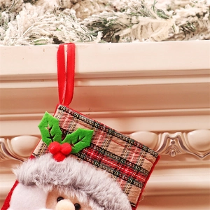 Gros plan d'une chaussette de Noël à carreaux avec Père Noël accrochée à la cheminée