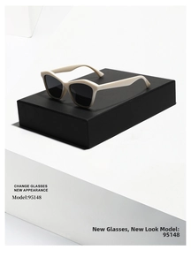 Detail view of stylish beige cat-eye sunglasses with dark lenses on a black display stand
