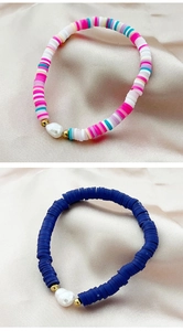 Detail of colorful heishi clay bead bracelets with white baroque pearls and gold accents