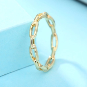 Gros plan d'une bague à maillons plaquée or 18 carats sur fond bleu clair épuré