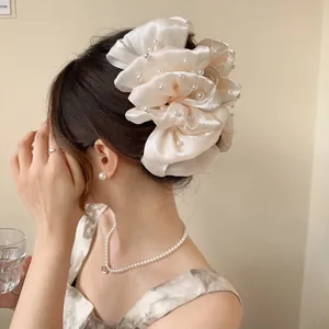 Dettaglio di un fermaglio per capelli champagne con perle e rete indossato dalla modella