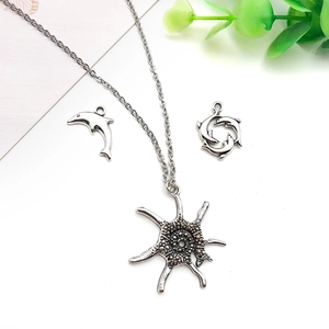 Macro detail of antique silver ocean charms featuring dolphins and textured sea-inspired alloy pendants