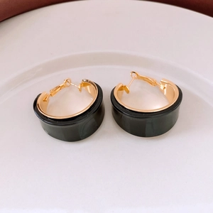 Close-up of vintage black resin C-shaped hoop earrings with 18K gold plated metal trim