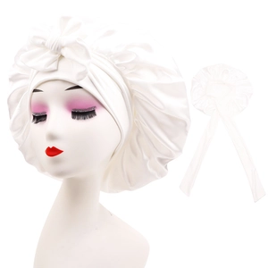 Close-up of white satin sleep cap with a large bow detail and adjustable ribbon ties