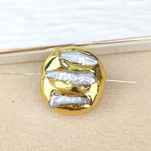 Macro view of a gold plated irregular freshwater pearl bead on a thin metal wire