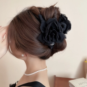 Détail d'une grande pince à cheveux rose en satin noir sur un chignon élégant