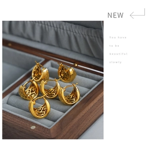 Detailed close-up of 18K gold-plated U-shaped earrings with hollow patterns on velvet