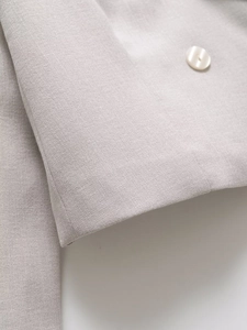 Close-up of linen-textured blazer cuff featuring detailed stitching and a pearl button