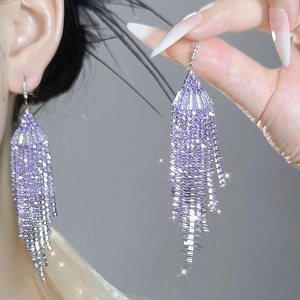 Detail showing elegant purple tassel earrings with sparkling rhinestones worn by a model
