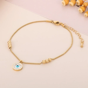 Close-up of golden evil eye charm and snake chain anklet with lobster clasp