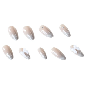 Cat eye press-on nails in nude gradient with white 3D bows and sparkling rhinestones