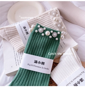 Detail of rib-knit socks in green and beige featuring elegant pearl and flower accents