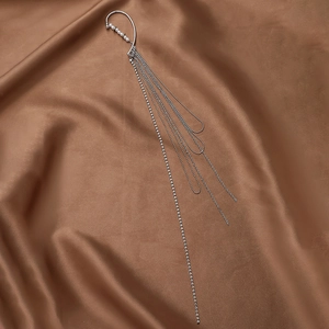 Silver long tassel ear hook with rhinestones and faux pearls on brown silk background