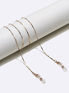 Detail of golden metal eyewear chain with white rubber loops on a white pedestal