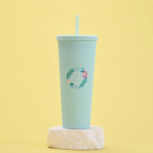 Detail of mint green studded tumbler with BEST Mom EVER floral emblem on yellow backdrop