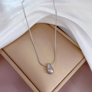 Close-up of silver teardrop pendant on snake chain inside a beige jewelry gift box