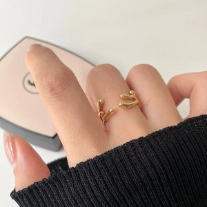 Close-up of a minimalist gold irregular liquid lava ring worn on model's finger